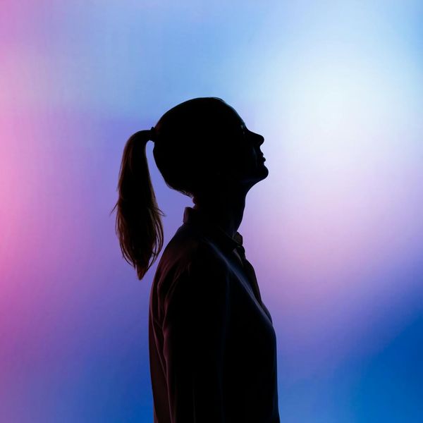 Silhouette of a person in a powerful yoga warrior pose against a mint-colored background.